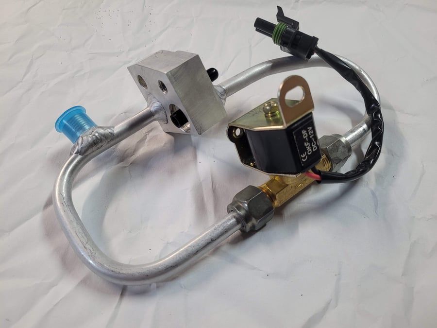 Metal valve assembly with silver tube, black solenoid, blue cap, and wiring on a white cloth background