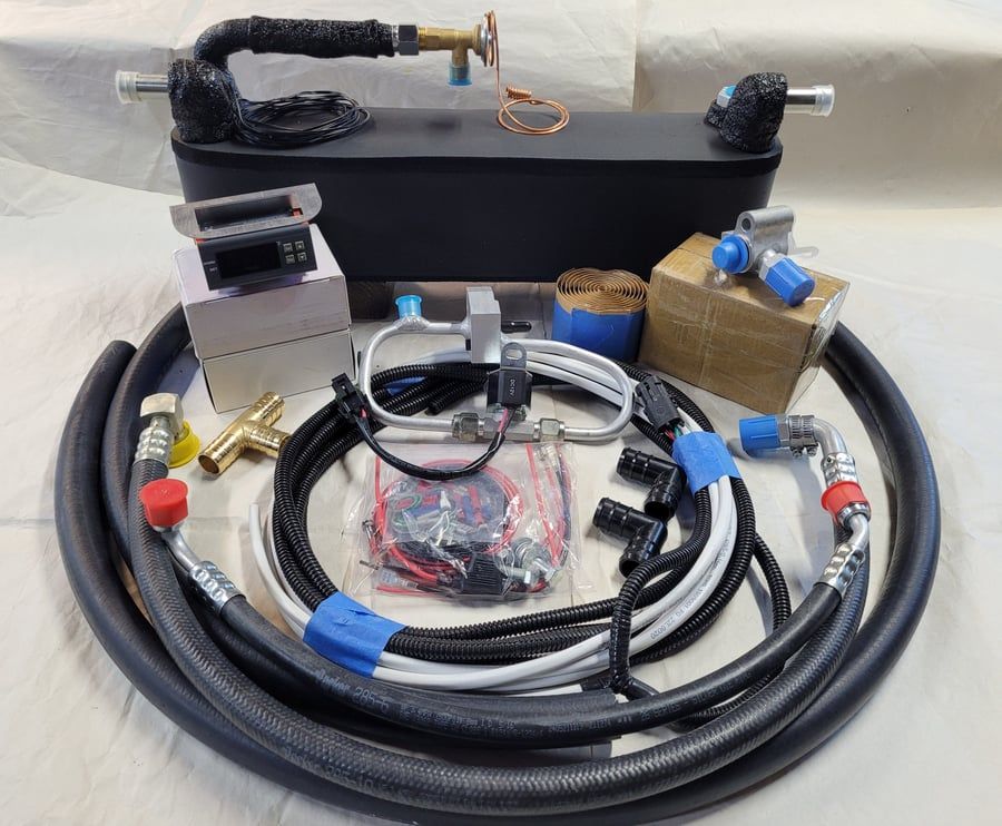 Assorted cables, connectors, and hardware parts arranged on a table with a black box and coiled hoses.