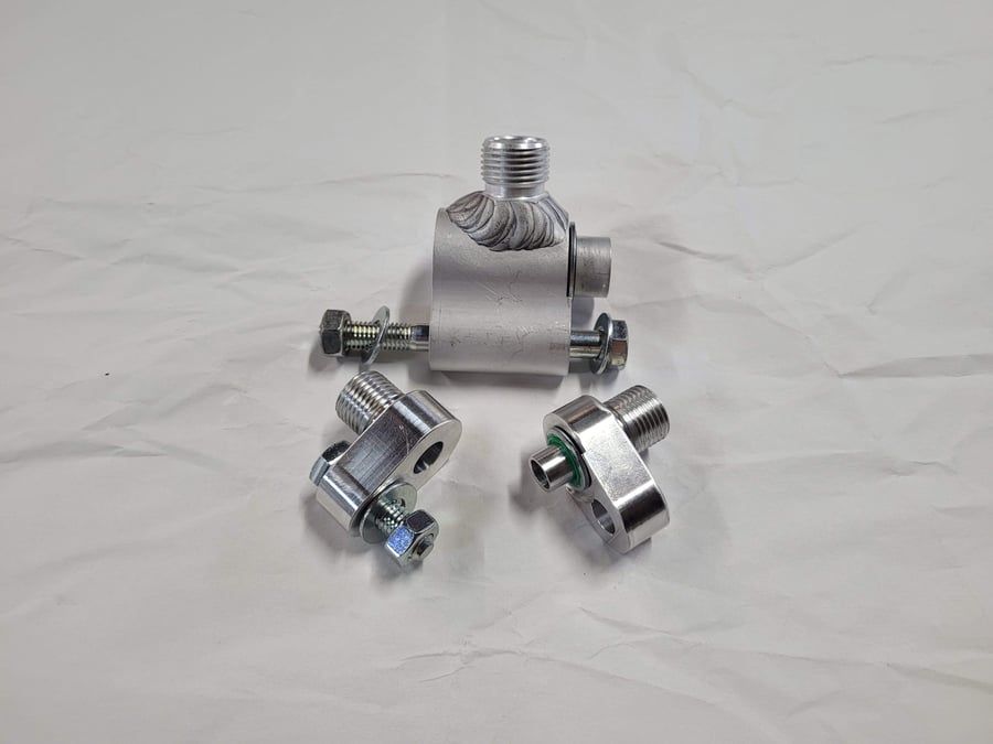 Three shiny chrome metal fittings on a white background, one centered with two smaller pieces below it