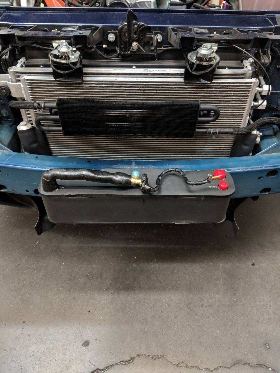 Front view of a blue car with the bumper removed, exposing the radiator and front-mounted cooler.