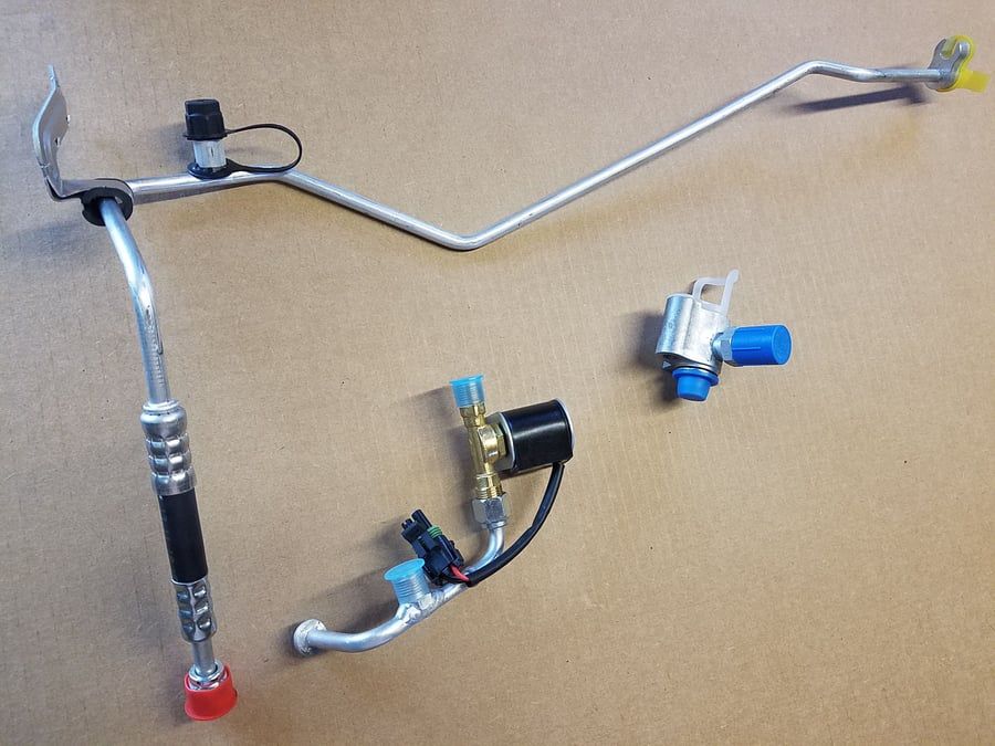 Assorted metal bicycle parts, including handlebars, brakes, and clamps, on a tan surface