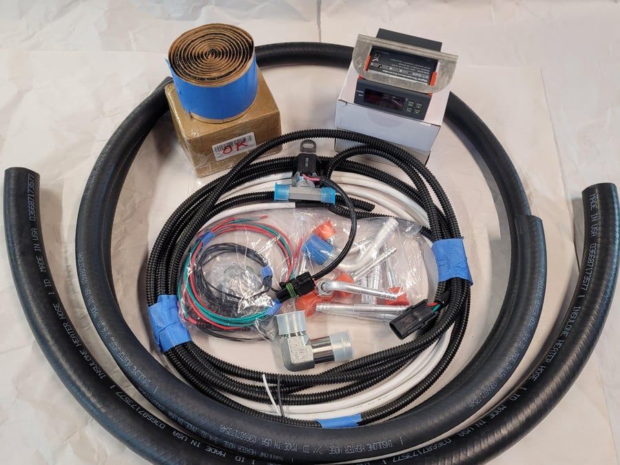 Coiled black hose with clear tubing, wires, and a small digital gauge on a white surface.