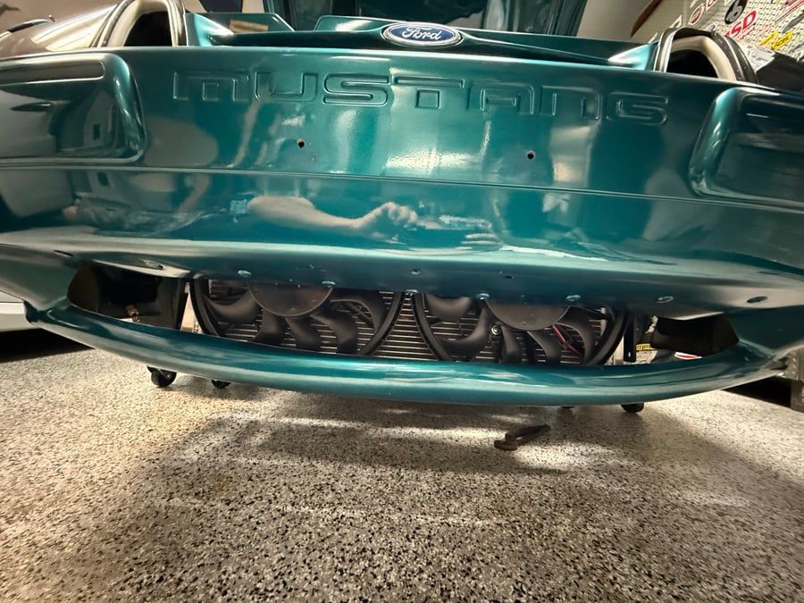 Teal sports car front bumper with exposed radiator and lower grille damage