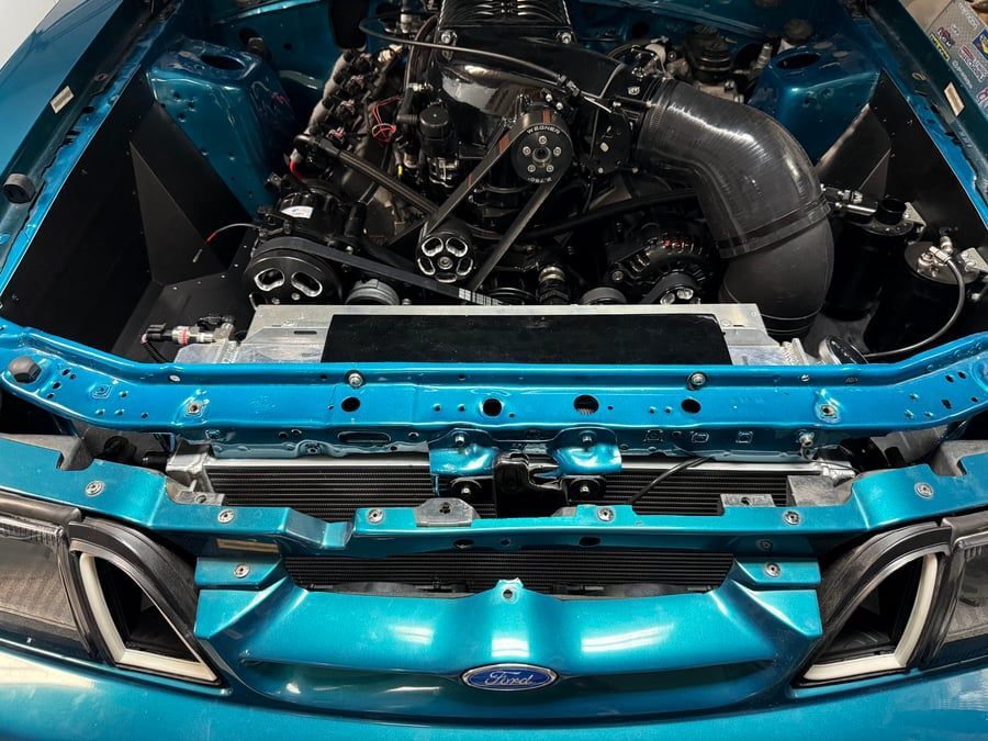 Open blue car hood showing engine bay and front grille