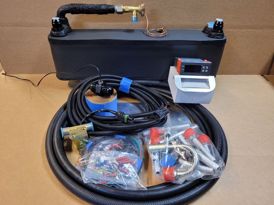Black metal tank with hose, coiled cable, and assorted parts on a table