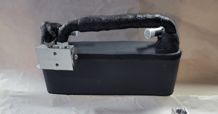 Black portable device with a curved black handle and a small gray metal plate attached on the side