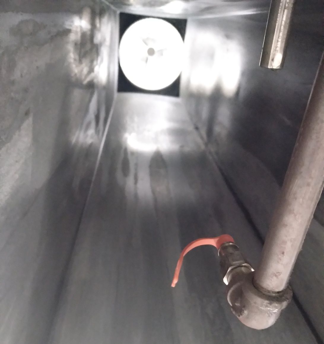 A pipe with an orange handle is going through a metal tunnel