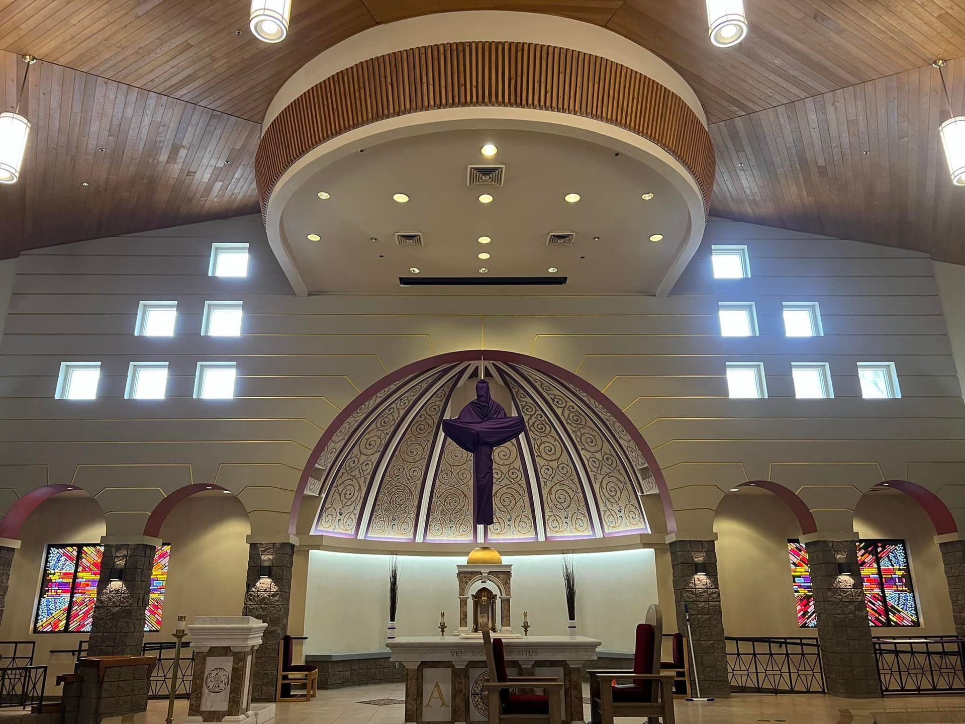 A church with a cross on the altar and stained glass windows