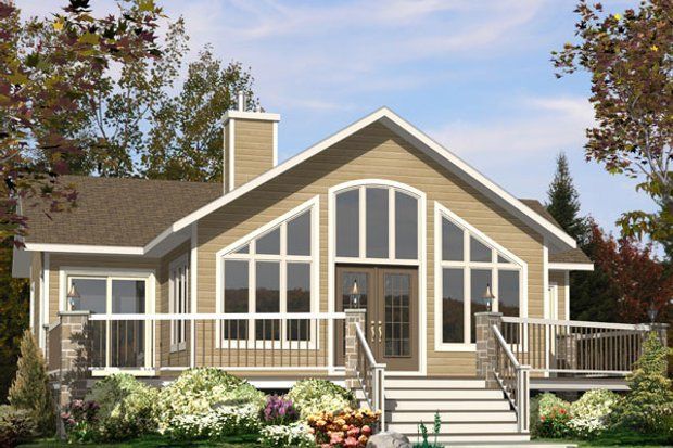 Tan house with large arched windows, front porch, and chimney, surrounded by trees.