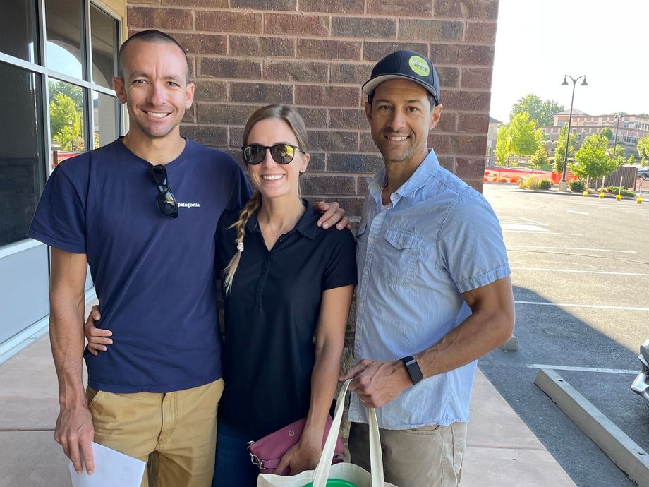 Three people are posing for a picture in front of a brick building.