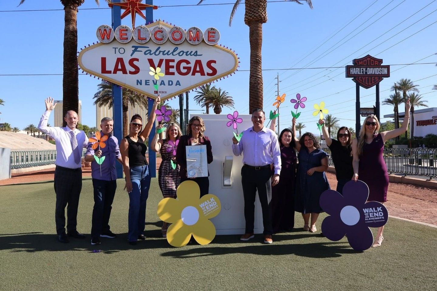 Group of people posing by the Welcome to Las Vegas sign with large flower props