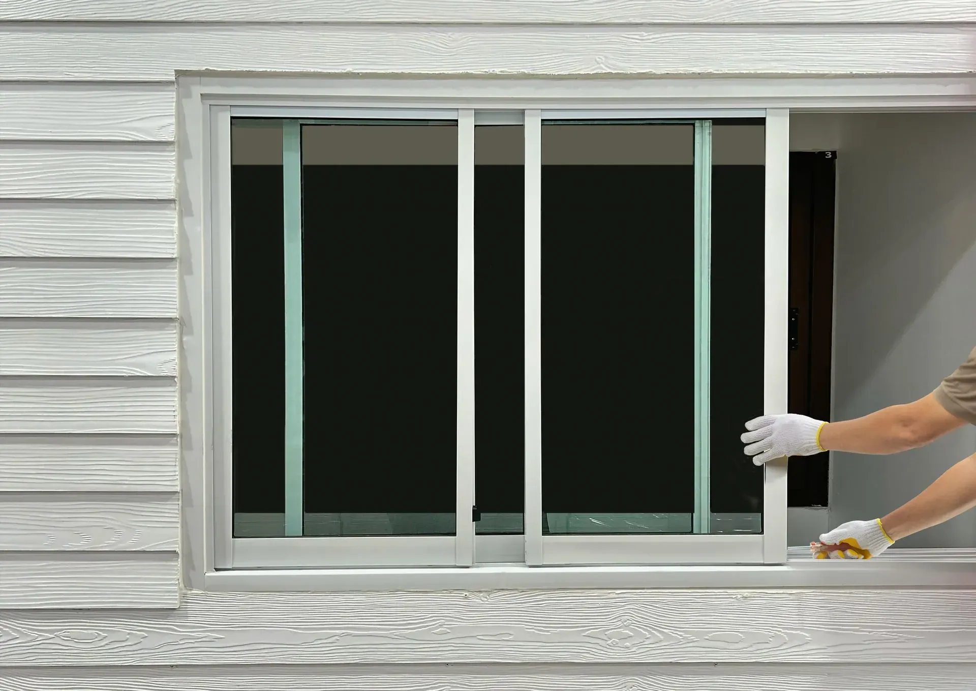 Person opening a sliding window on a white house.