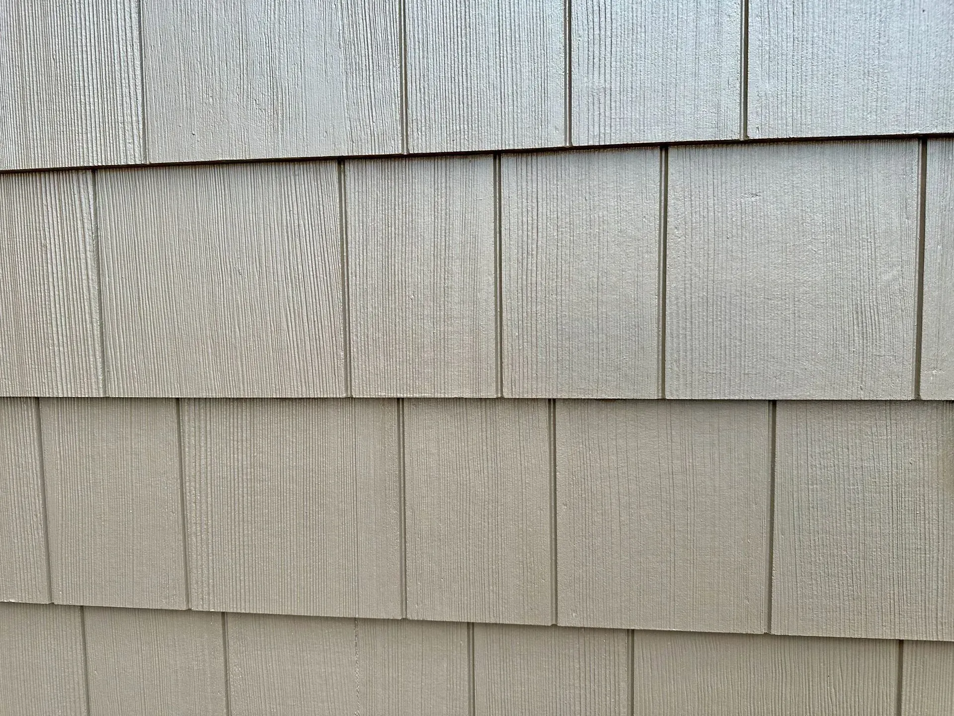 Siding Chicago IL Close-up of overlapping, light gray, wood-grain textured siding.
