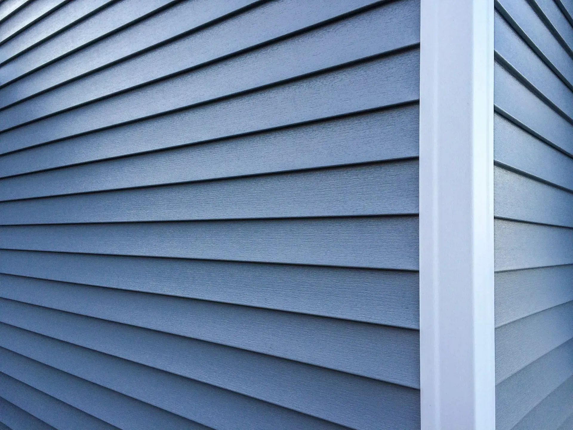 Siding Chicago IL Blue horizontal siding on a building, corner with white trim.