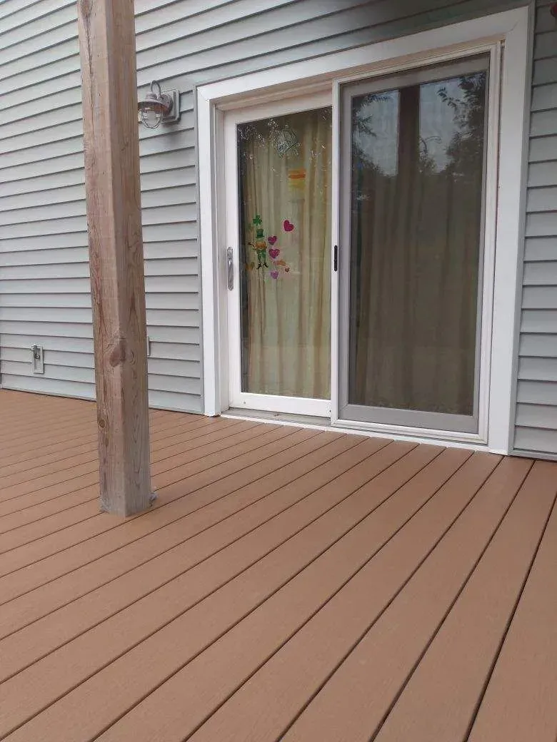 GARAGE. deck leads to a sliding glass door with white frame on a gray siding house.