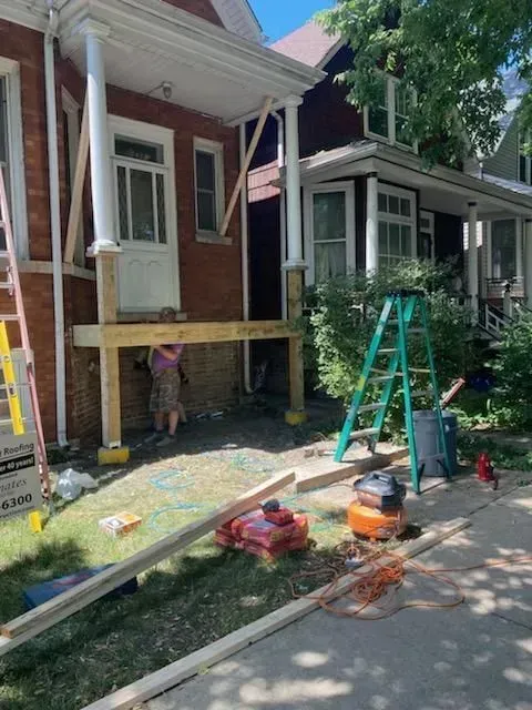 Construction work on a porch with wooden supports, tools, and a person.