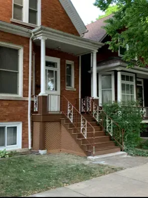 Exterior services Chicago IL Two-story brick building with brown porch, steps, and white railing. 