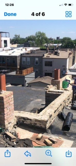 GARAGE. Rooftop view with brick chimney and weathered wall, surrounding buildings on a sunny day.