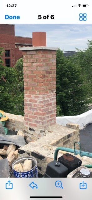 GARAGE. Brick chimney on a rooftop with surrounding green trees, a partly cloudy sky, and various tools.