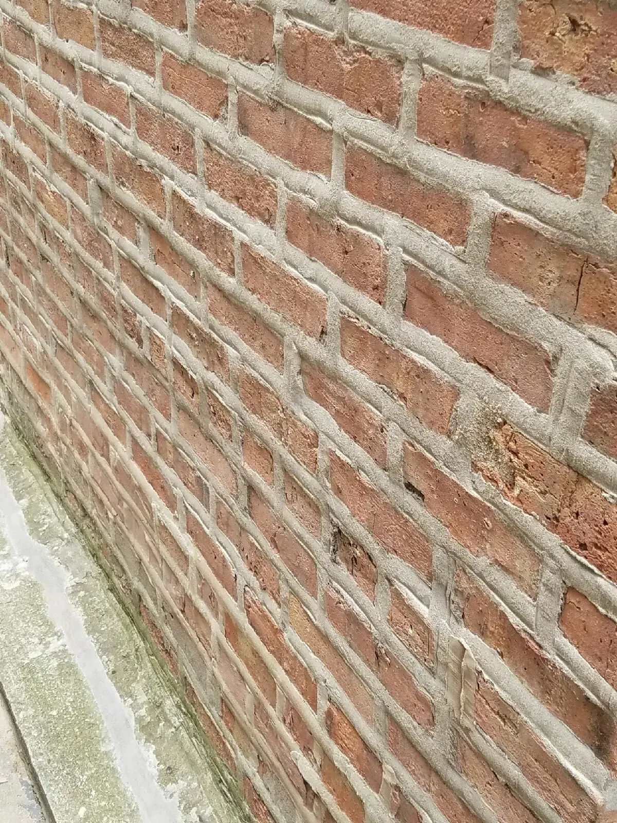 Gallery. Red brick wall with gray mortar joints, viewed at an angle.