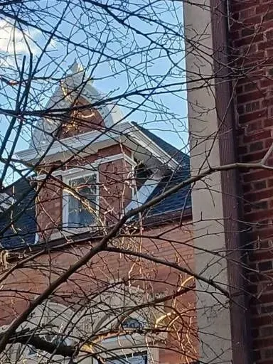 Gallery. Red brick building with a decorative white-capped turret against a blue sky, framed by bare tree branches.