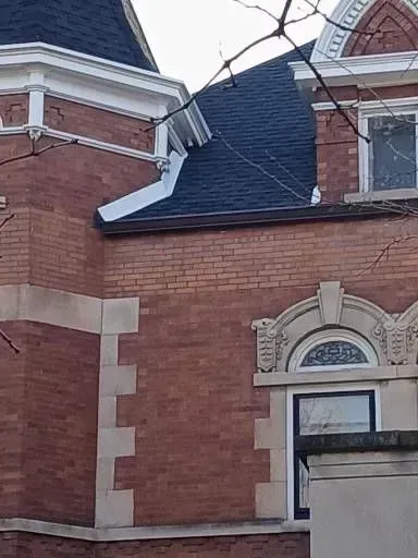 Gallery. Brick building exterior with dark roof and white trim. Decorative window details.