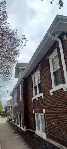 Gallery. Red brick building with white trim, gray roof, and a sidewalk. Cloudy sky.