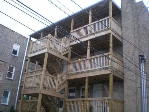 Wooden multi-level outdoor staircase attached to a brick building; power lines overhead.
