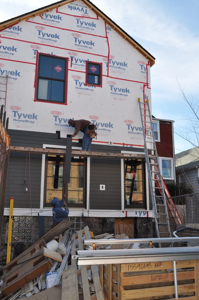 A man is working on the side of a house with styrofoam on it
