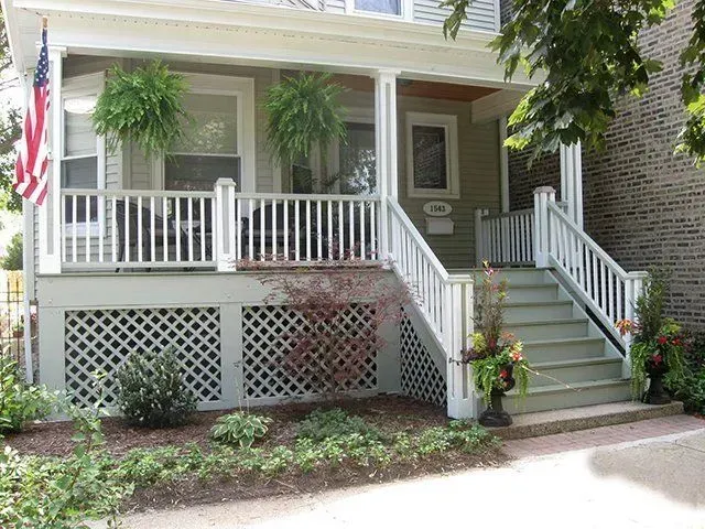 A two-story house with a front porch; an American flag hangs on the left.