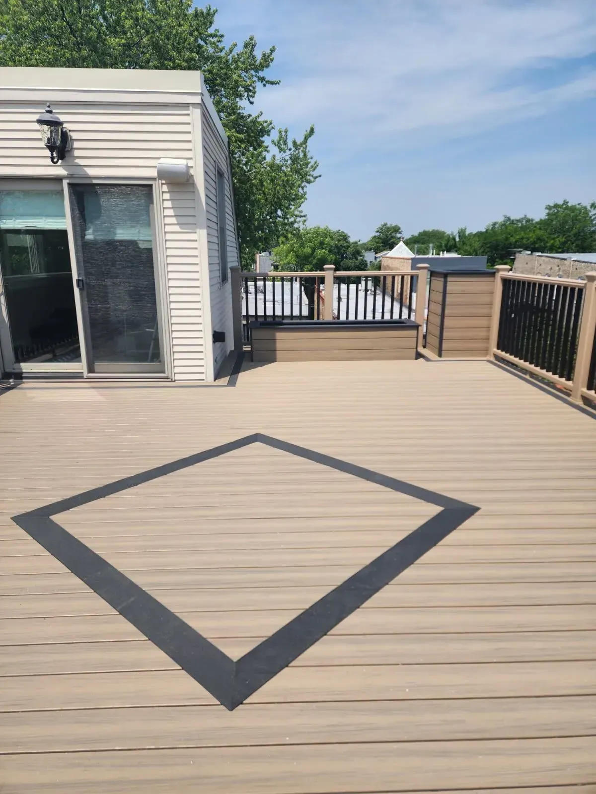 Gallery. Composite deck with black diamond inlay, sliding door, and black railings.
