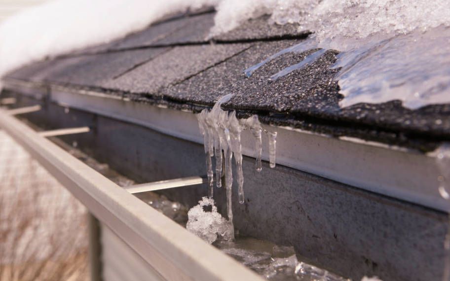 Icicles are hanging from a gutter on a roof.