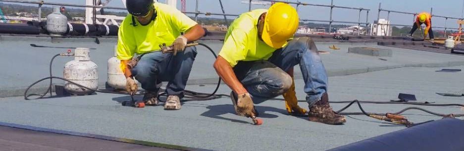 Two construction workers are working on a roof.
