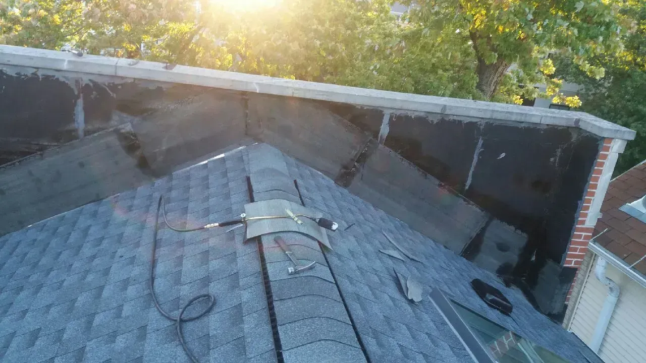 Gallery. View of a roof with asphalt shingles, a flat black section, and a chimney.