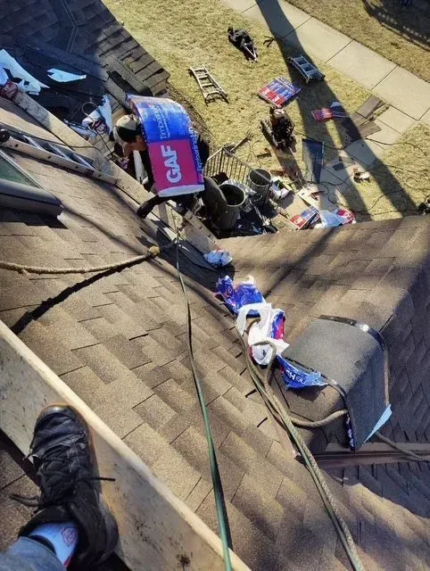 Gallery. Person working on a roof with supplies, including GAF roofing material.