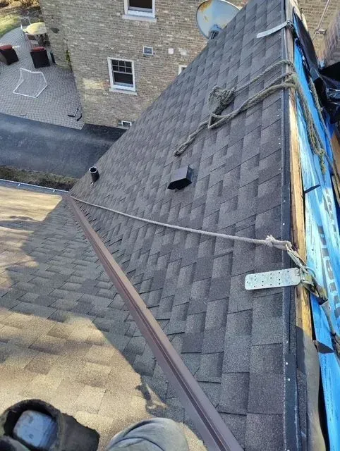 Gallery. View from rooftop showing asphalt shingles, ropes, and blue tarp.