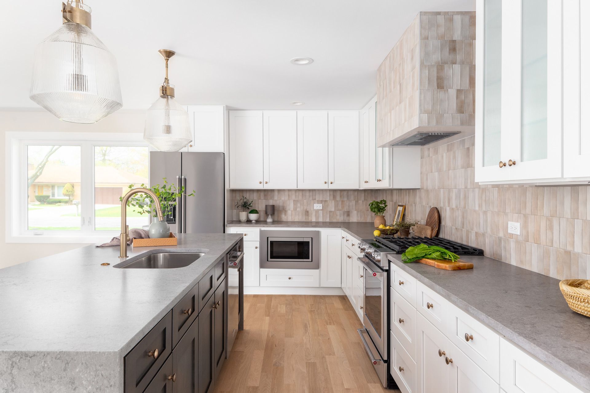 A kitchen with white cabinets, stainless steel appliances, a sink, and a large island