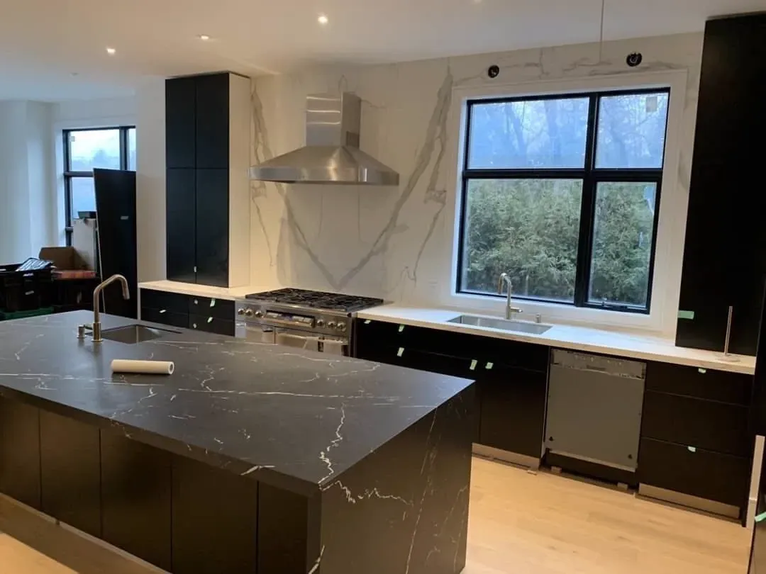 A kitchen with black cabinets and a large island in the middle