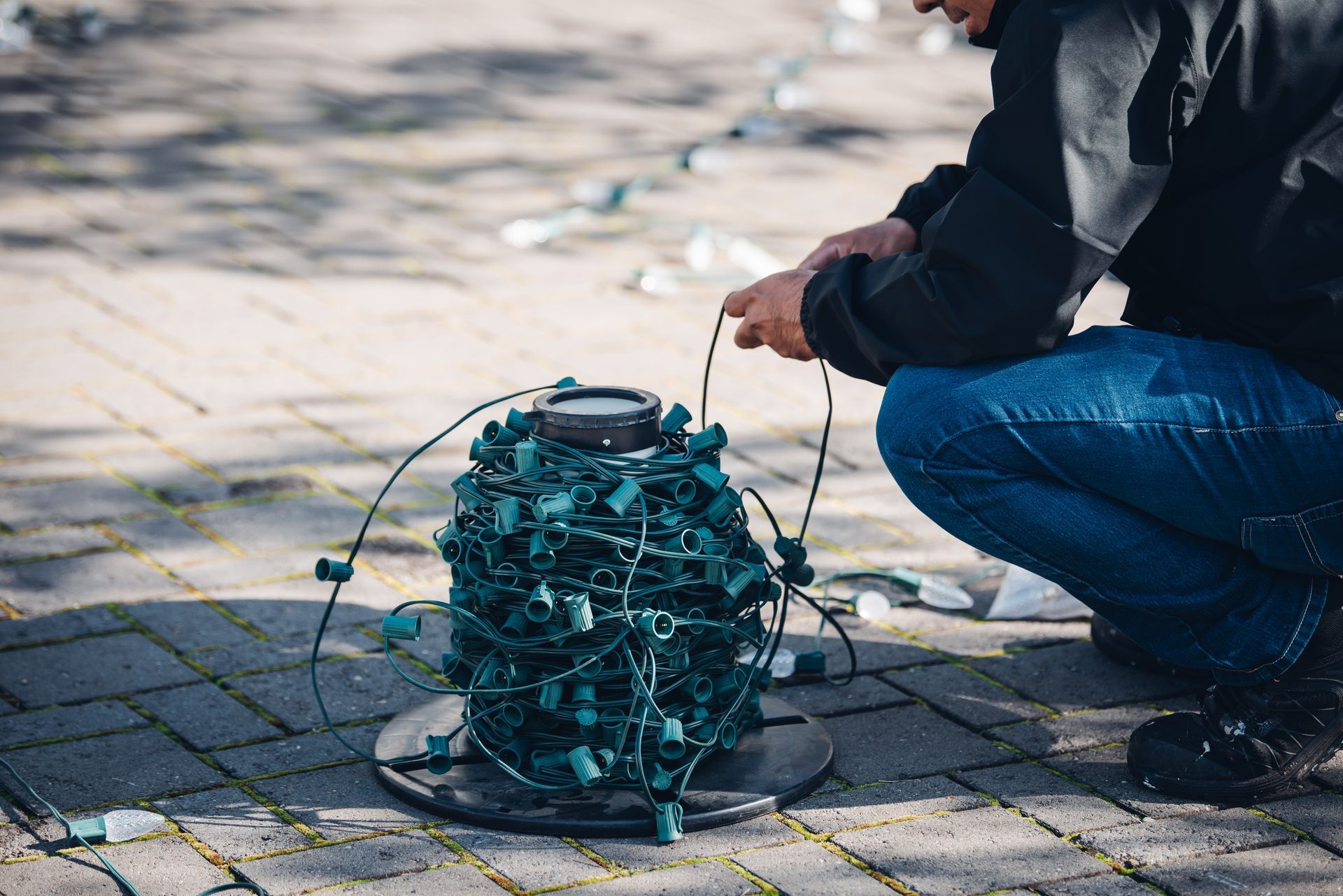 A man is kneeling down next to a bunch of christmas lights.