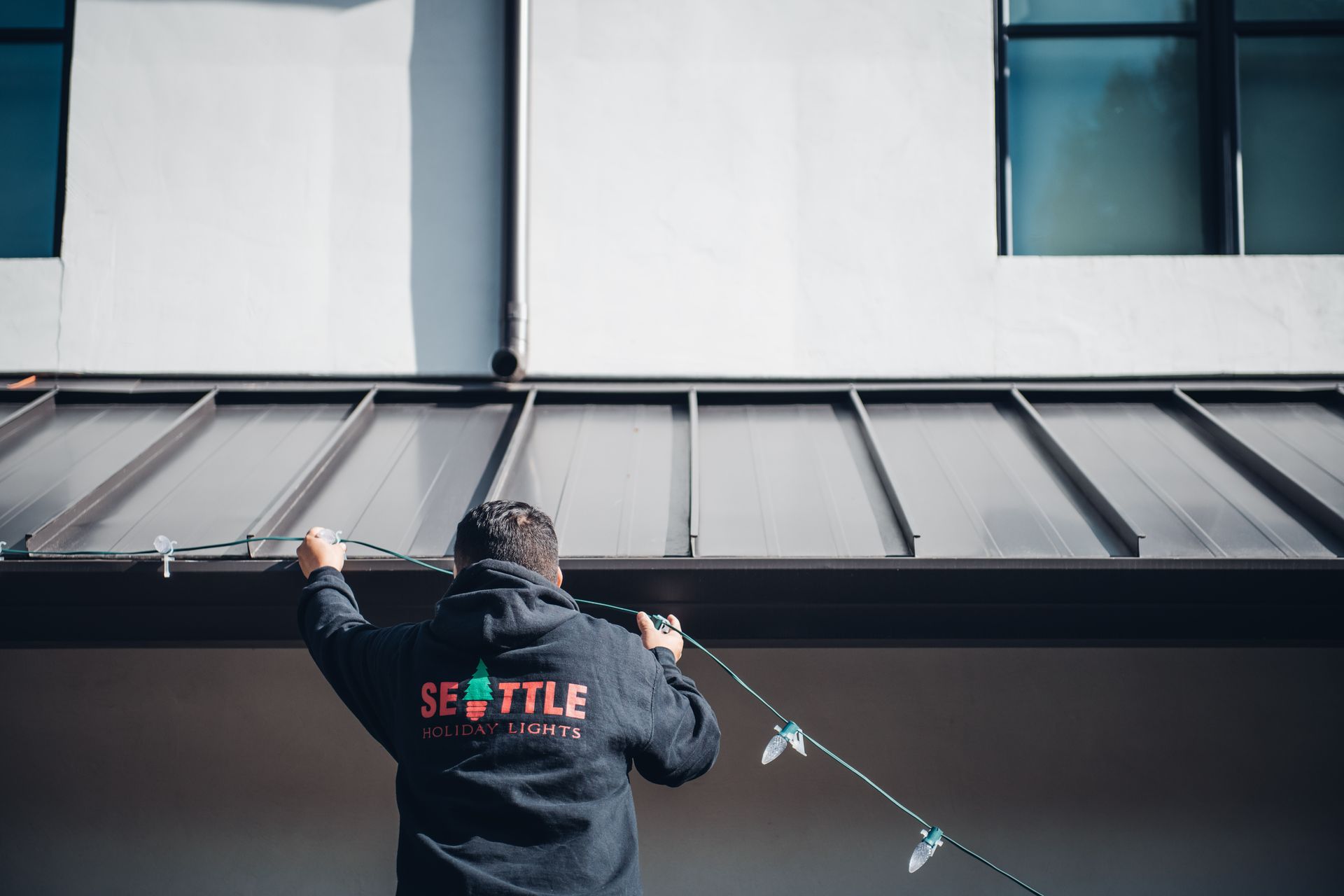 A man is cleaning the gutters of a building with a hose.