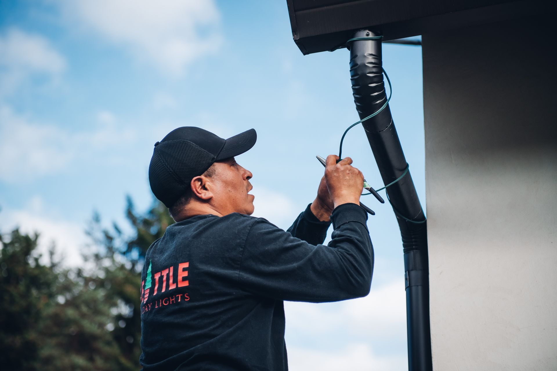A man is working on a gutter on the side of a building.