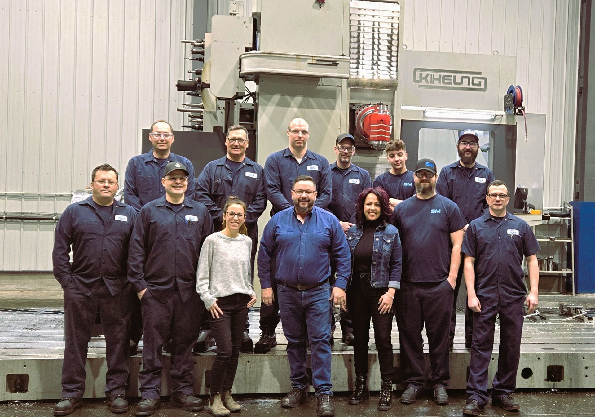 Un groupe de personnes pose pour une photo devant une machine.