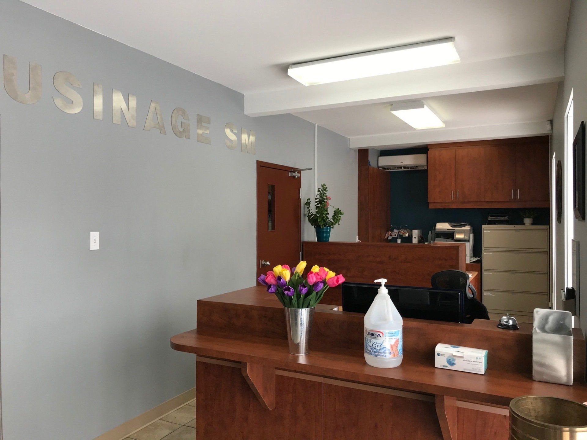 Un bureau d'accueil avec un vase de fleurs et une bouteille de désinfectant pour les mains dessus.