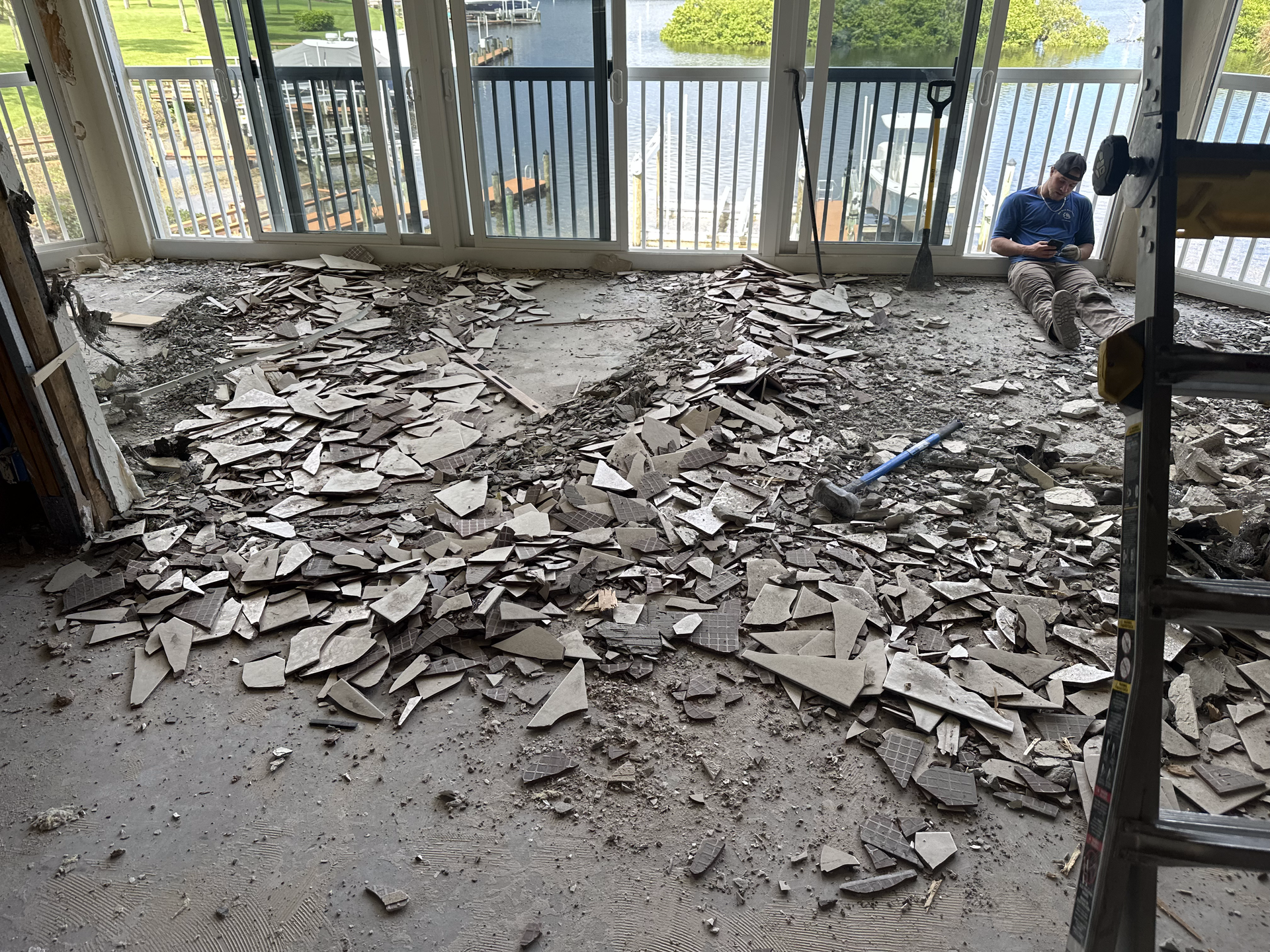 A man is sitting on a pile of broken tiles in a room.