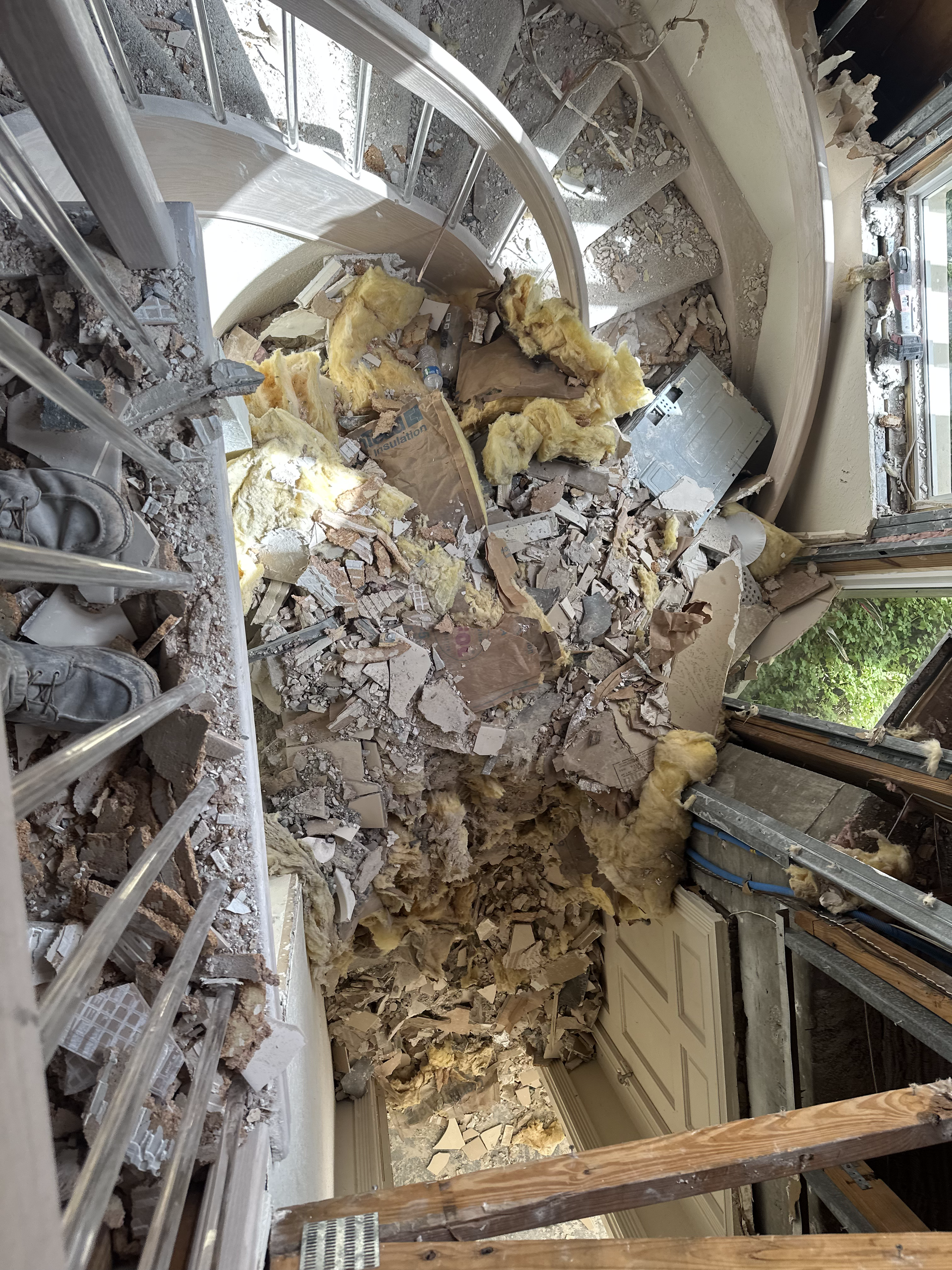 A room with a lot of rubble on the floor and stairs.