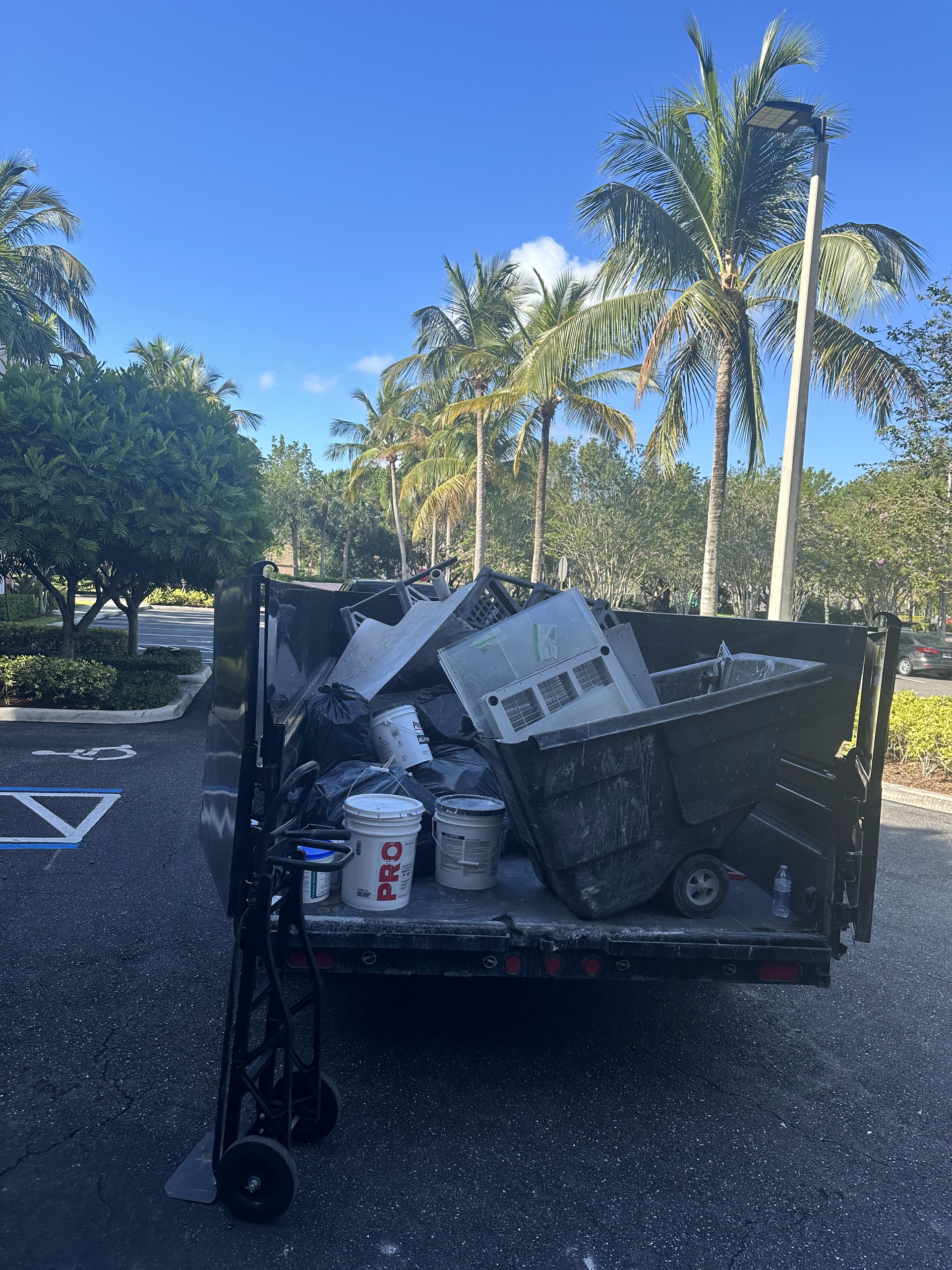 A dumpster filled with trash is parked in a parking lot.