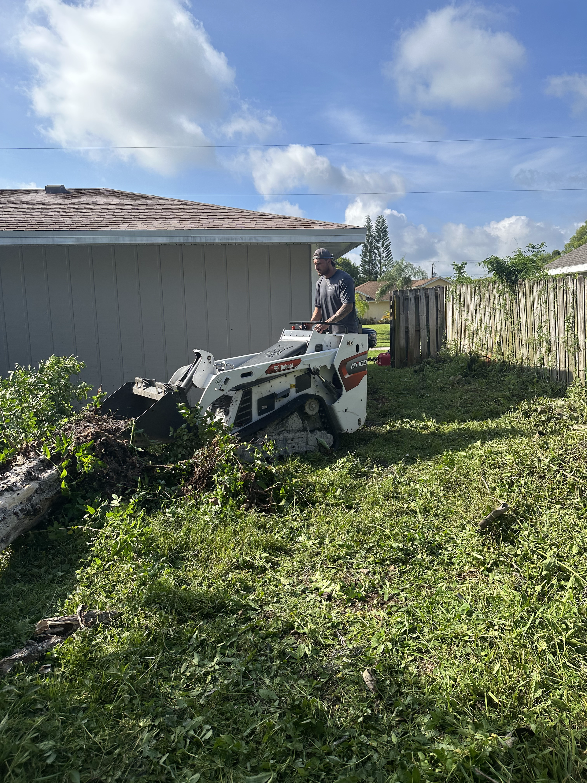 A man is driving a tractor through a lush green yard.