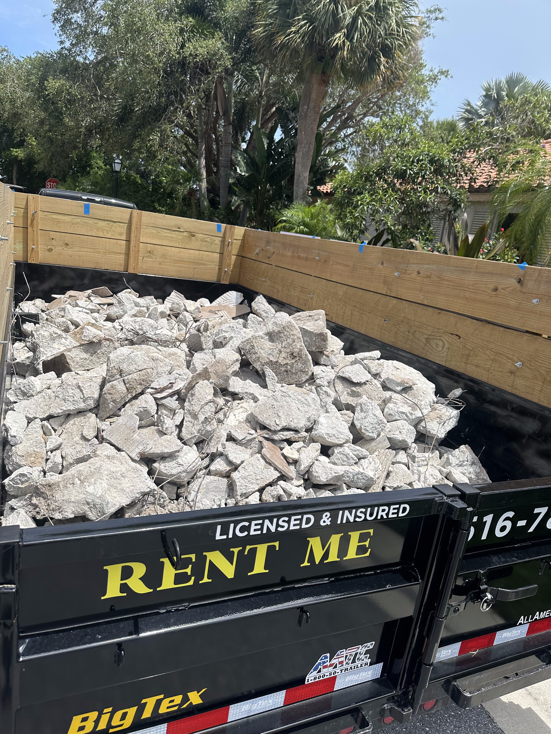 A dumpster filled with rocks is parked on the side of the road.