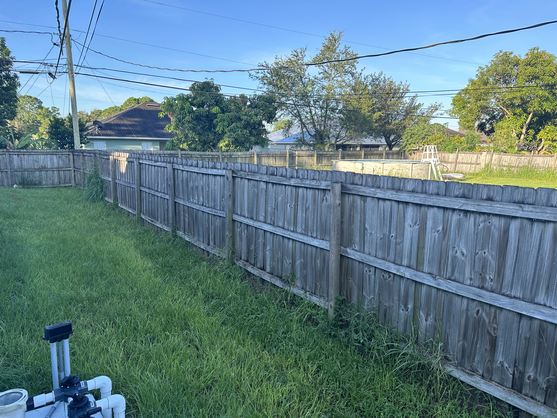 A wooden fence surrounds a lush green yard.