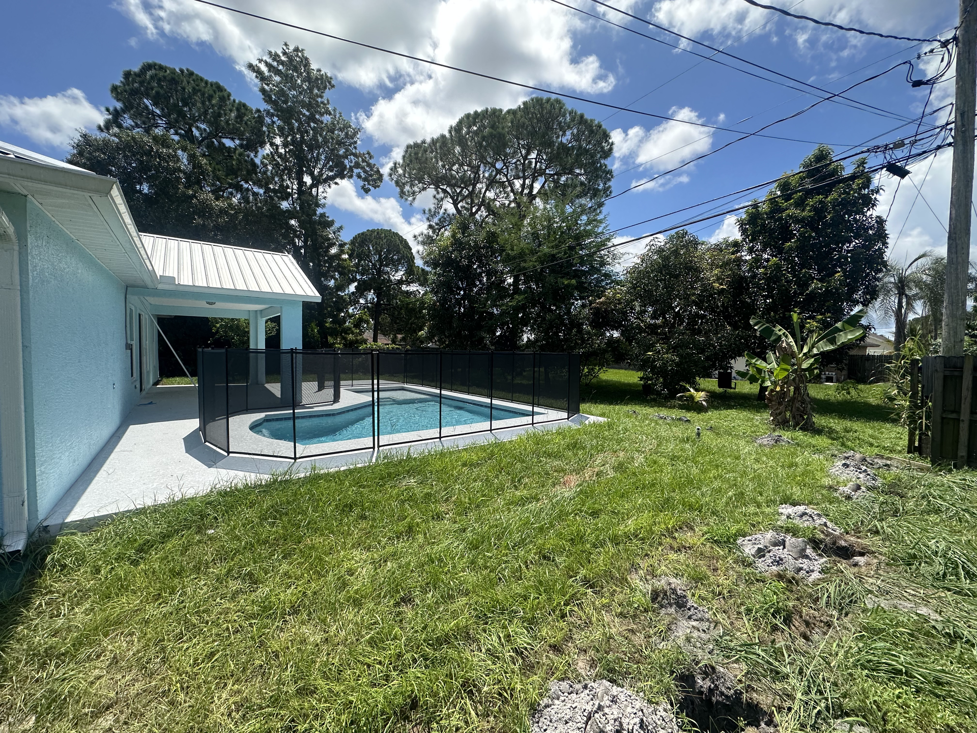 The backyard of a house with a pool and a fence surrounding it.